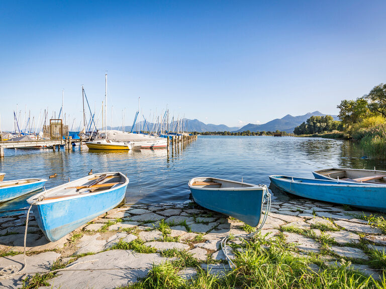 Blick auf Boote am Chiemsee an sonnigem Tag mit Berg-Panorama