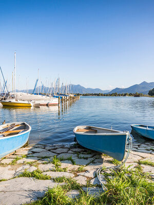 Blick auf Boote am Chiemsee an sonnigem Tag mit Berg-Panorama