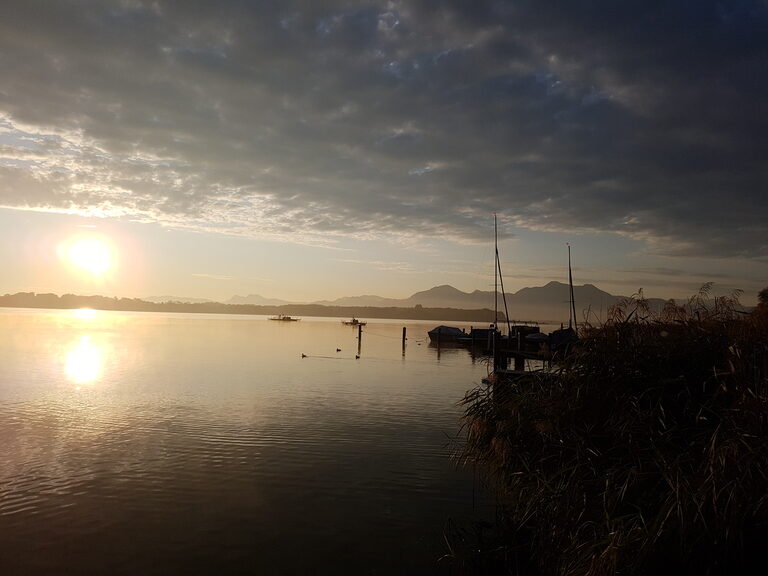 Der Chiemsee glitzert bei Sonnenuntergang.