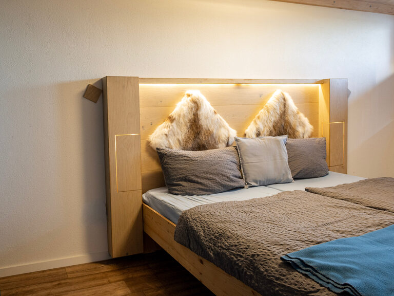 Bett im Schlafzimmer in Ferienwohnung  mit modernem hölzernem Bett mit Beleuchtung